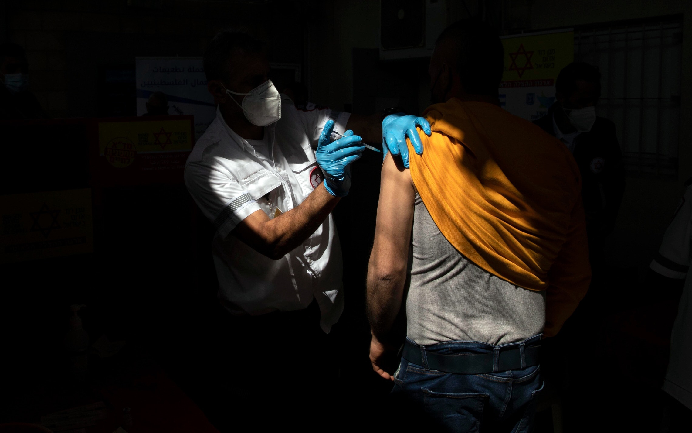 פועל פלסטיני מקבל חיסון נגד קורונה של חברת מודרנה במעבר טרקומייה בגדה המערבית, 8 במרץ 2021 (צילום: AP Photo/Sebastian Scheiner)