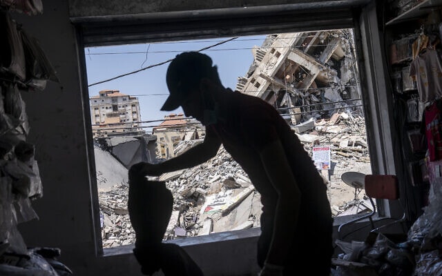 עלי אל-באבלי, בן 24, פותח את חנות הבגדים שלו כדי לבחון את הנזק אחרי הפגזות חיל האוויר בעיר במהלך מצבע &quot;שומר החומות&quot;, 25 במאי 2021 (צילום: AP Photo/John Minchillo)