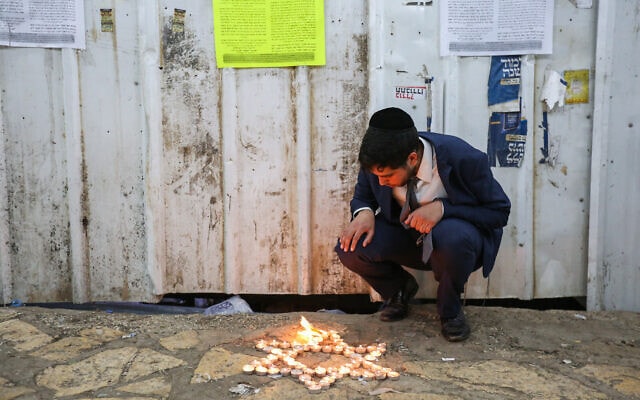 חרדי מדליק נרות בזירת הארוע של האסון בהר מירוון, 1 במאי 2021 (צילום: דוד כהן/פלאש90)