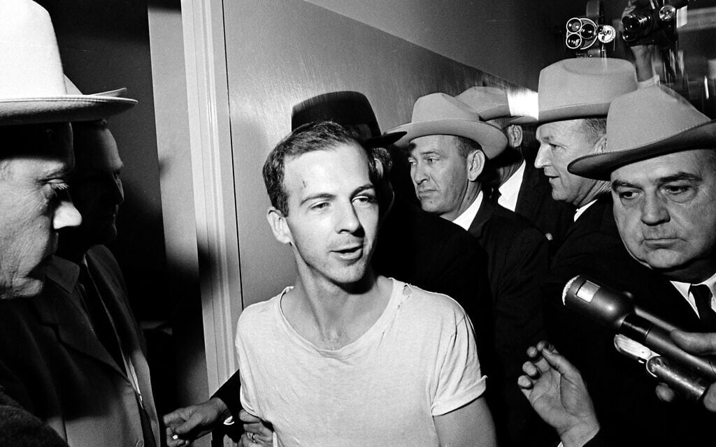 לי הארווי אוסוולד מוקף בשוטרים כשהוא מובל במסדרונות תחנת המשטרה בדאלאס לחקירה יום למחרת ההתנקשות בנשיא ג&#039;ון קנדי, 23 בנובמבר 1963 (צילום: AP Photo)