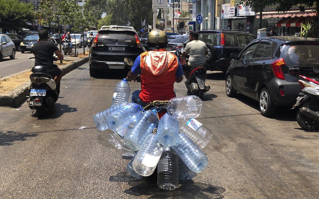 רוכב טוסטוס בלבנון נוסע עם בקבוקים ריקים כדי לאגור דלק (צילום: AP Photo/Hussein Malla)