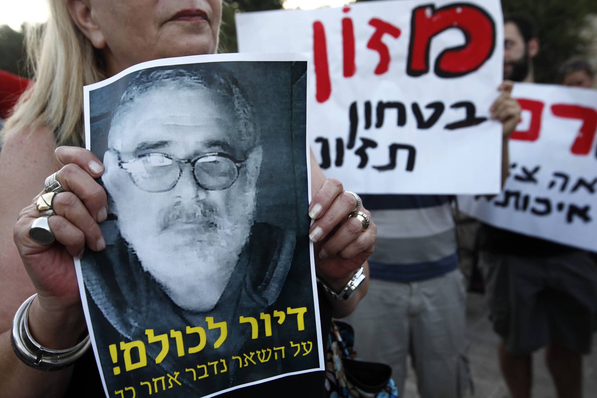 מפגינה נושאת את תמונתו של משה סילמן, שהצית את עצמו למוות כמה ימים קודם לכן, 18 ביולי 2012 (צילום: מרים אלסטר/פלאש90)