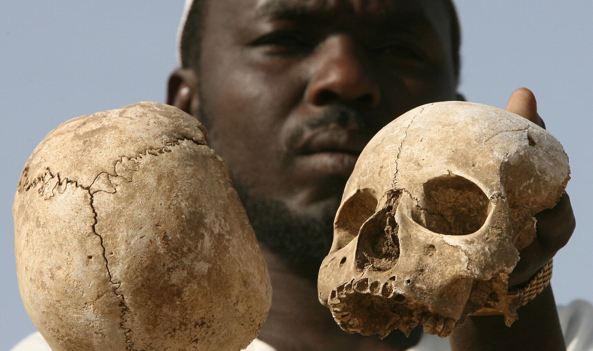 ניצול סודאני מדארפור בשם אבראהים מחזיק גולגולות אדם ליד קבר המוני שבו לדבריו נמצאים שרידיהם של 25 מחבריו ובני הכפר שלו, בפאתי העיר מוקג&#039;ר במערב דארפור, סודאן, 23 באפריל 2007 (צילום: AP/Nasser Nasser)