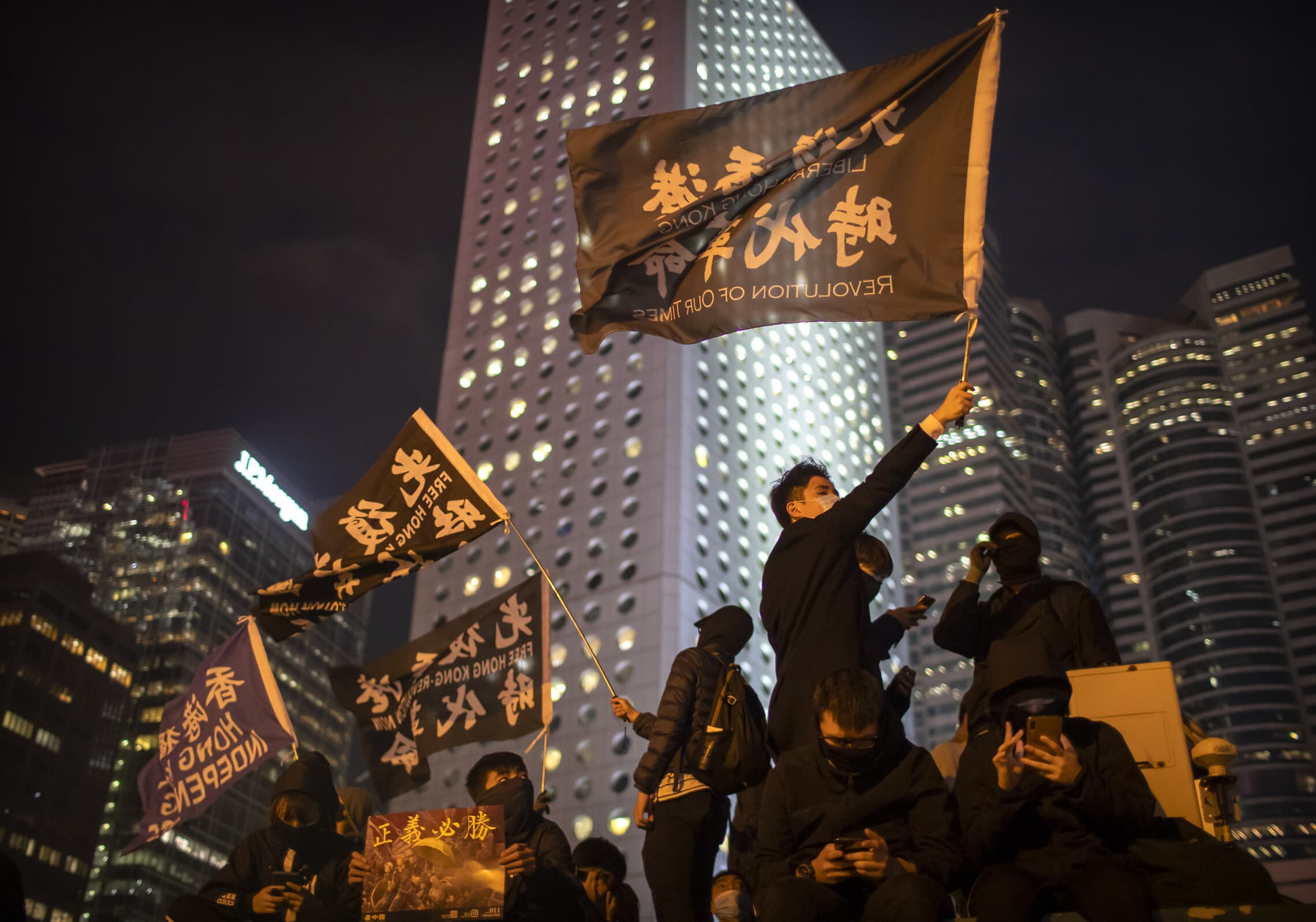 מפגינים בהונג קונג מניפים דגלים עם הסלוגן "מהפכה עכשיו",12 בדצמבר 2019 (צילום: AP Photo/Mark Schiefelbein)