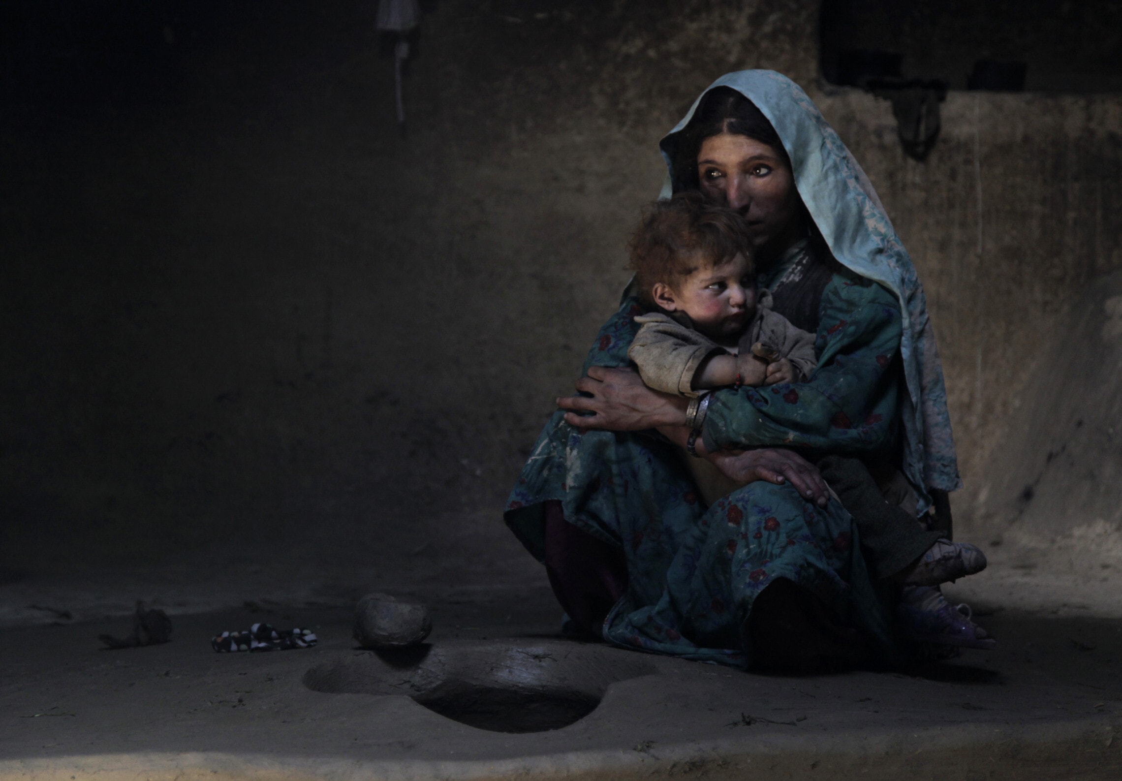 אפגנית כפרית מרגיעה את ילדה בן השנה אחרי עישון אופיום בבוקר עם בני משפחתה, 13 ביולי 2009 (צילום: AP Photo/Julie Jacobson)
