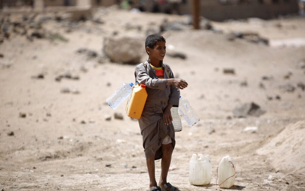 ילד סוחב מכלי מים ממרכז חלוקה באזור צנעה, בתימן (צילום: AP Photo/Hani Mohammed)