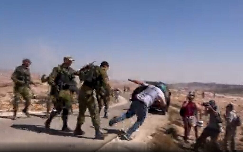פעיל זכויות אדם ישראלי נדחף מאחור ומוטח אל הקרקע על-ידי קצין בדרגת רס"i, צילום מסך מתוך סרטון פייסבוק של פעילי השלום
