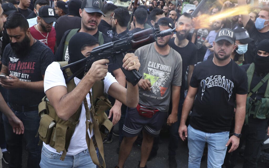 פעיל תנועת אמל השיעית יורה באוויר במהלך הלוויה של אחד ההרוגים במהומות בביירות ב-14 באוקטובר 2021 (צילום: AP Photo/Bilal Hussein)