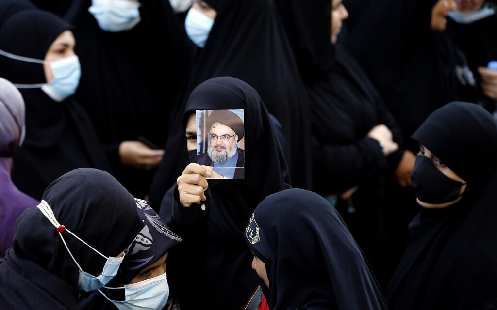 אישה לבנונית מחזיקה בתמונה של מזכ&quot;ל החזבאללה חסן נסראללה בהלוויה של שלושה תומכי חזבאללה שנהרגו במהומות בביירות ב-14 באוקטובר 2021 (צילום: AP Photo/Bilal Hussein)
