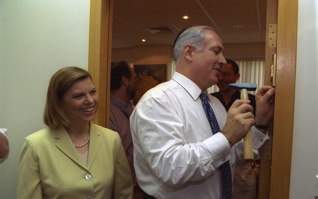 ראש הממשלה היוצא בנימין נתניהו קובע מזוזה במשקוף דלת הכניסה ללשכתו החדשה בירושלים, כשלצידו רעייתו שרה, 7 ביולי 1999 (צילום: אבי אוחיון/לע&quot;מ)