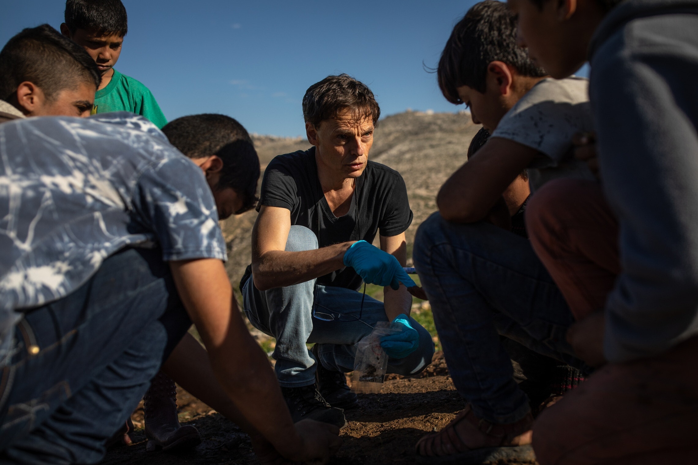 הסביבתן יעקב גארב מציג לילדים פלסטינים מדיר סאמת את האדמה שהוא דוגם למחקרו (צילום: Tamir Kalifa)