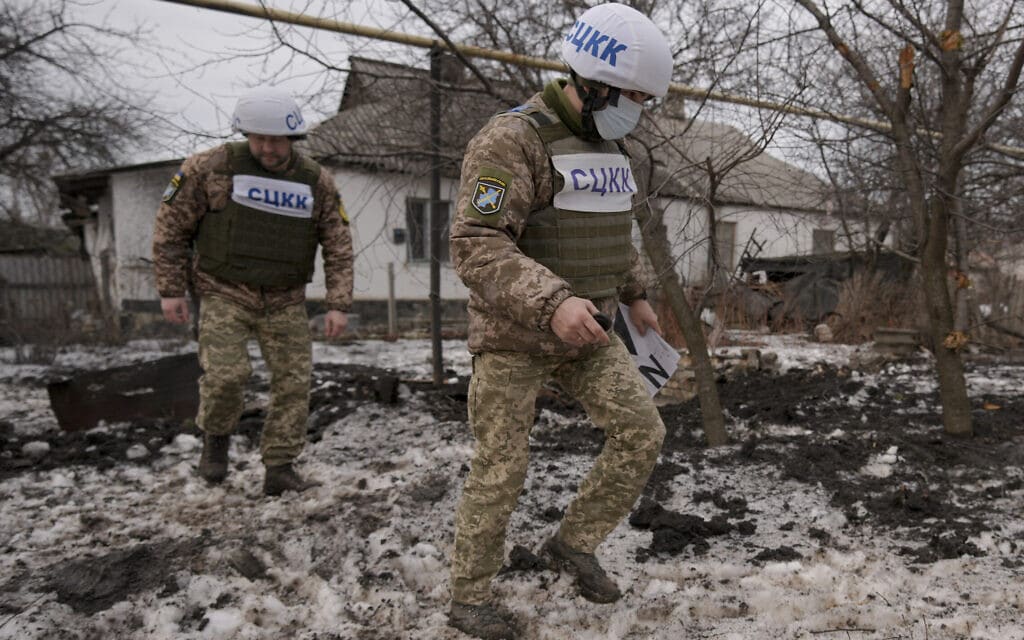 אנשי המרכז המשותף לפיקוח ולתיאום הפסקת האש (JCCC) בוחנים נזק שנגרם מירי פגז במחוז לוהנסק שבמזרח אוקראינה, 17 בפברואר 2022 (צילום: Vadim Ghirda, AP)