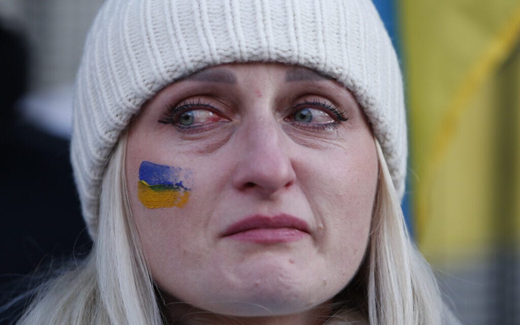 אישה בוכה בזמן שירת ההמנון האוקראיני בהפגנה מחוץ לשגרירות רוסיה בלונדון, 26 בפברואר 2022 (צילום: AP Photo/David Cliff)