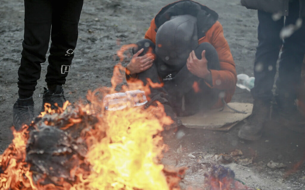 פליטים אוקראינים מנסים להתחמם ליד מעבר הגבול עם פולין, 28 בפברואר 2022 (צילום: AP Photo/Visar Kryeziu)