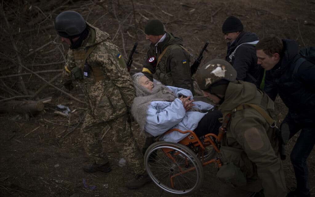 חיילים ואנשי שירות אוקראיניים מסייעים לקשישה באירפין להימלט מהקרבות, 7 במרץ 2022 (צילום: Emilio Morenatti, AP)