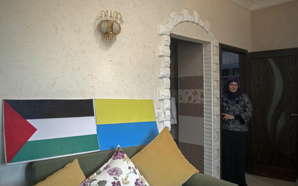 אילוסטרציה: אוקסנה אל־אסטל האוקראינית מצטלמת בסלון ביתה המקושט בכרזות של דגלי פלסטין ואוקראינה, חאן יונס, 13 במרץ 2022 (צילום: AP Photo/ Khalil Hamra)