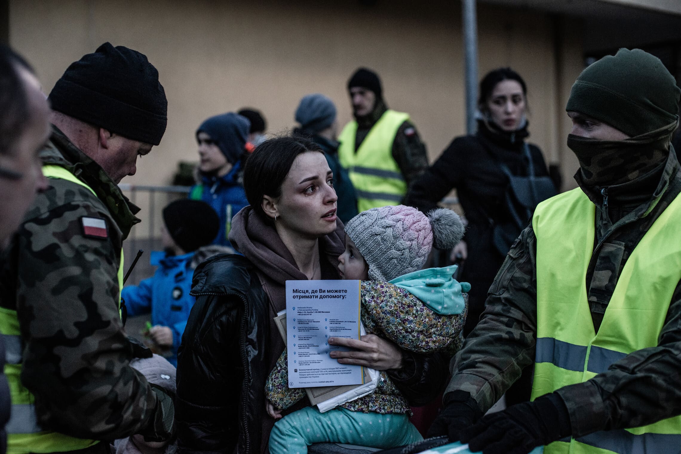 פליטה אוקראינית מוקפת חיילים ממשמר הגבול הפולניים. מרץ 2022 (צילום: גילעד שדה)
