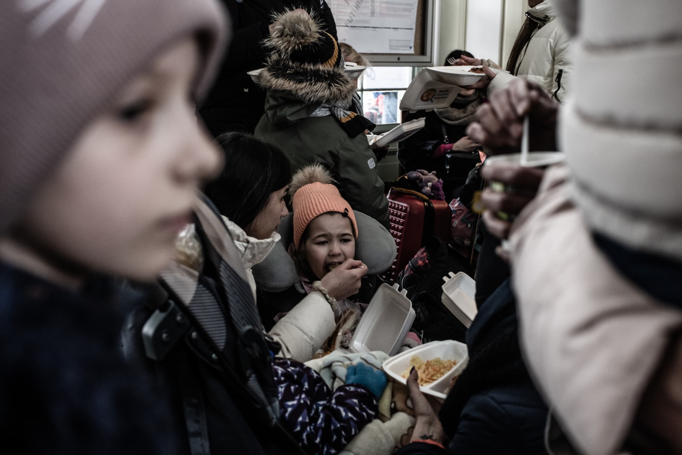 פליטה מאכילה את בתה באולם הנוסעים המרכזי בתחנת הרכבת פשמישל, פולין. פברואר 2022 (צילום: גילעד שדה)