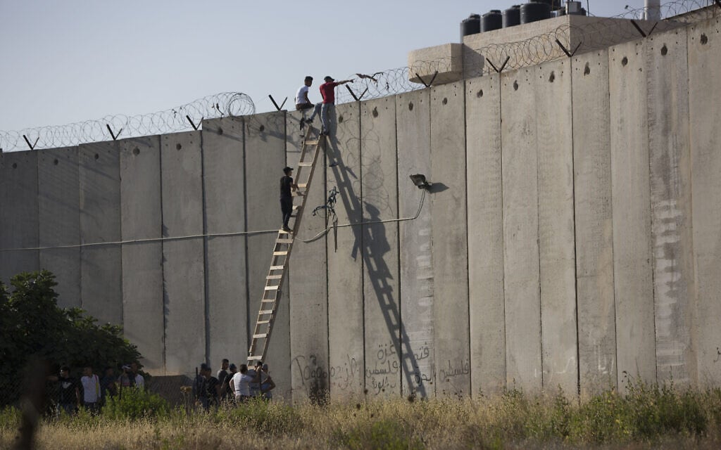 פלסטינים מטפסים על גדר ההפרדה ליד א-רם בדרכם לתפילות יום שישי באל-אקצא, 8 ביוני 2018 (צילום: AP Photo/Majdi Mohammed)