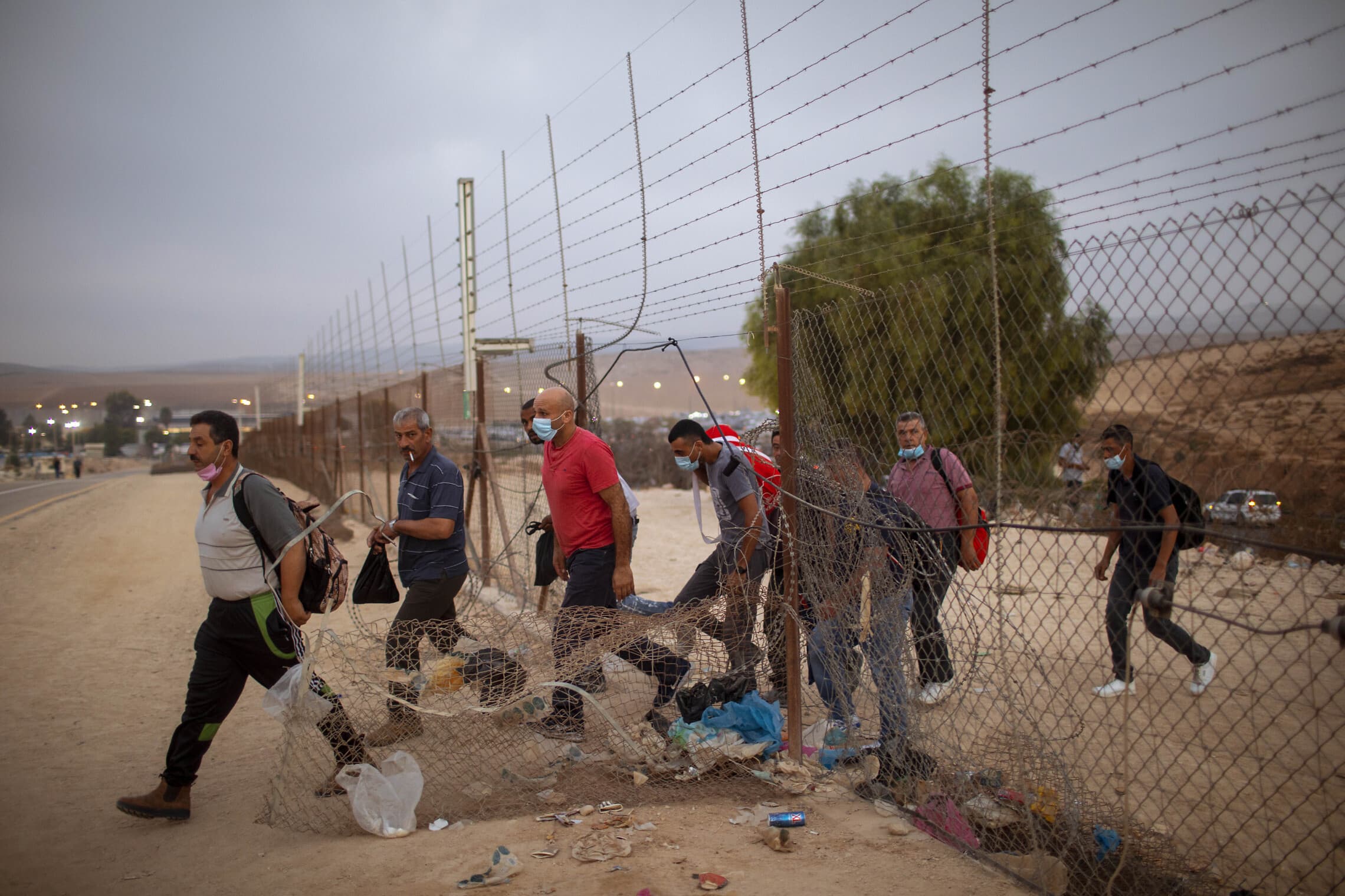 פועלים פלסטינים מהגדה המערבית חוצים דרך פרצה בגדר ההפרדה ליד חברון, ספטמבר 2020 (צילום: AP Photo/Oded Balilty)