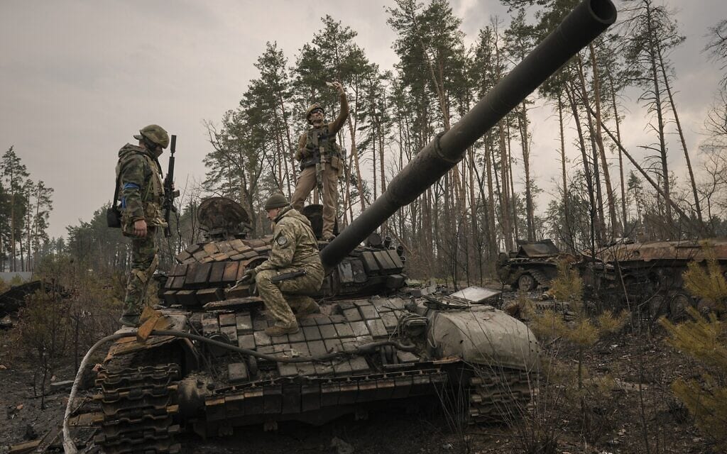 חיילים אוקראינים מצטלמים על טנק רוסי הרוס ליד קייב, 31 במרץ 2022 (צילום: AP Photo/Vadim Ghirda)