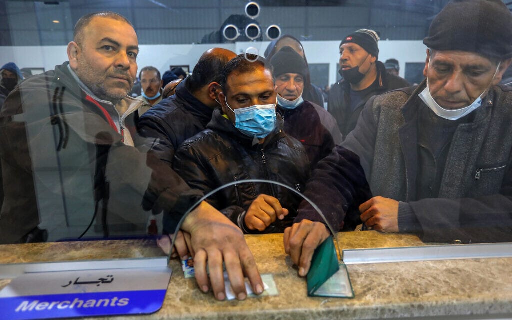 עובדים פלסטינים מעזה מציגים אישורי עבודה במעבר ארז, 13 במרץ 2022 (צילום: Attia Muhammed/Flash90)
