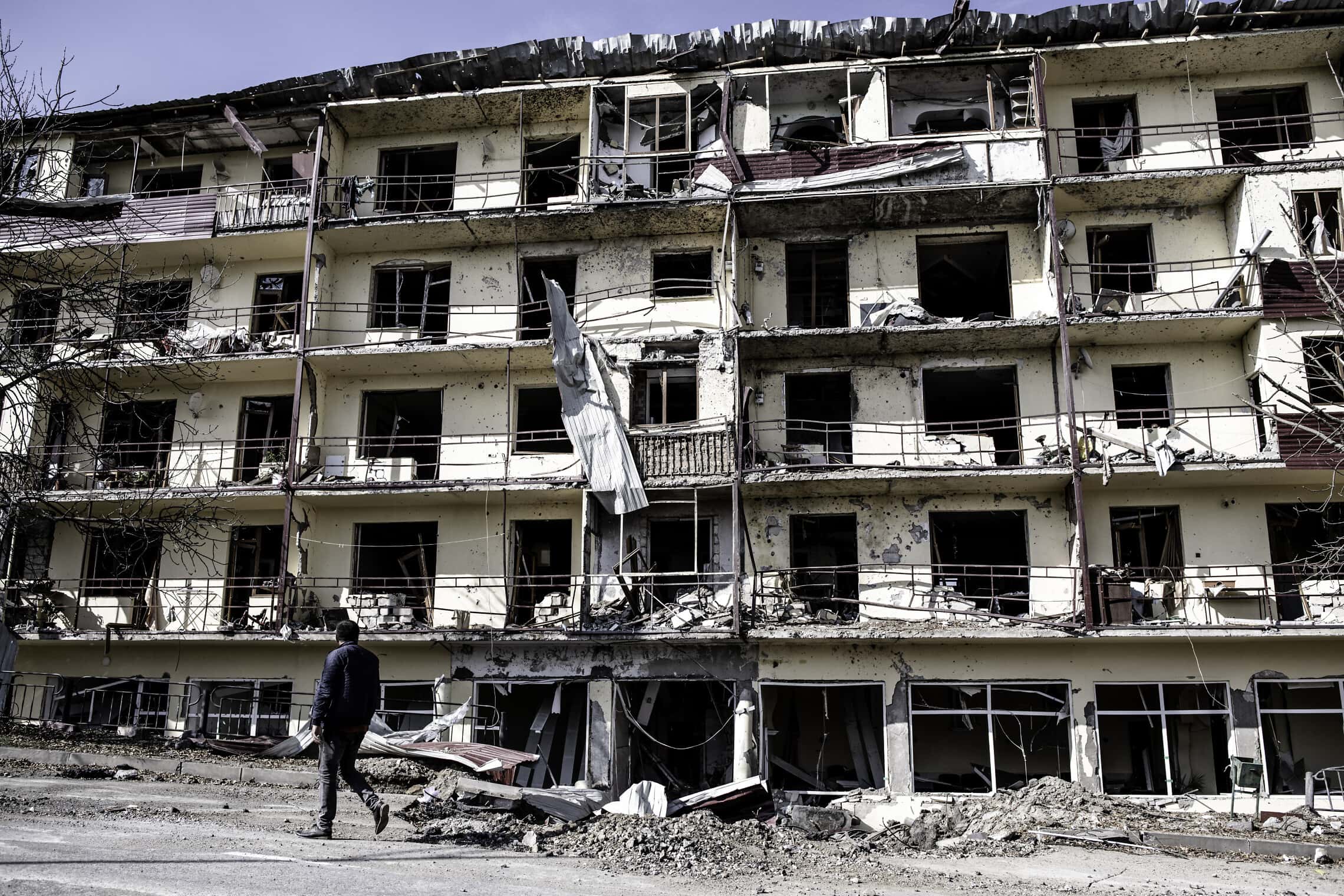 ארמני מנגורנו קרבאך הולך לצד בניין מגורים שהופגז על ידי אזרבייג&#039;ן בשושה, סוף אוקטובר 2020 (צילום: גילעד שדה)