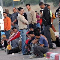 פועלים פלסטינים מהגדה המערבית המועסקים בישראל מחכים לאנשי הקשר שלהם אחרי שחצו את מחסום מכבים בכביש 443, יולי 2009