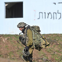 חייל בגדוד הצנחים במהלך אימון ברמת הגולן. על הבניין ברקע נרשם: "די למלחמות". ינואר 2022 (צילום: מיכאל גלעדי/פלאש90)