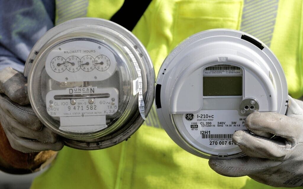 אילוסטרציה: טכנאי אנרגיה בחברת אדיסון מחזיק במונה חשמל רגיל ובמונה "חכם", אילינוי, ארה"ב, 6 בספטמבר 2013 (צילום: AP Photo/M. Spencer Green)