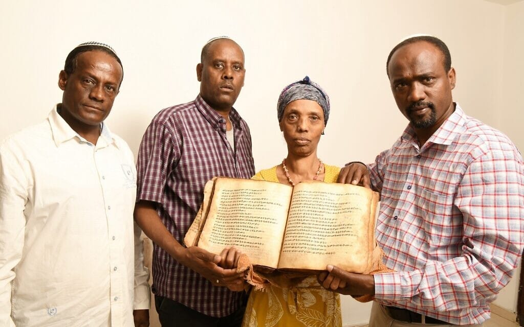 איינאו פרדה סנבטו ובני משפחתו אוחזים בספר העתיק שהחזירו מאתיופיה, בפברואר 2022 (צילום: יוסי זליגר)