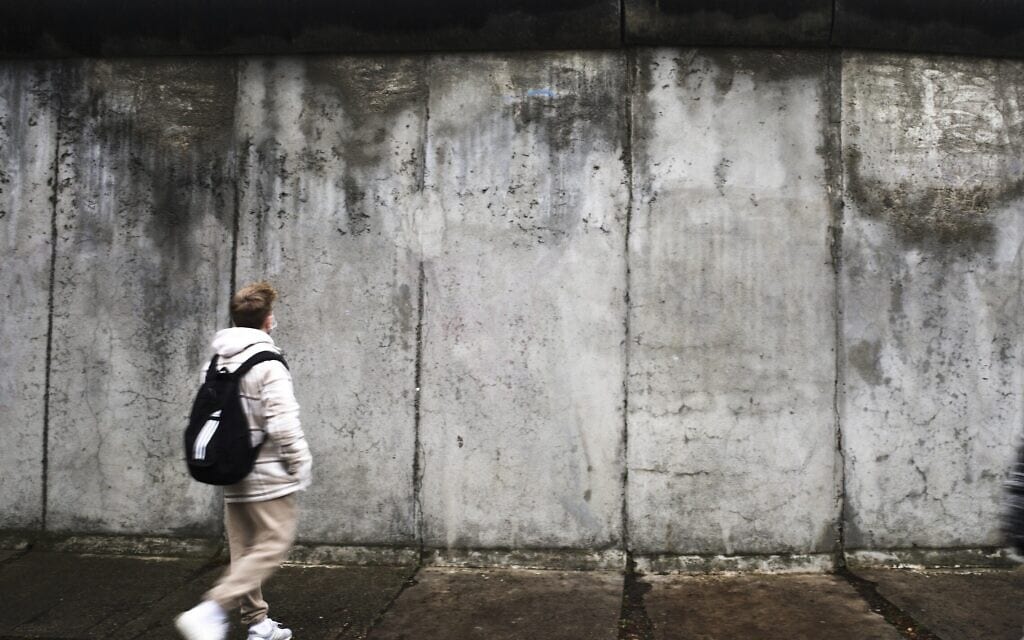 סטודנט חולף ליד חומת ברלין, 9 בנובמבר 2021 (צילום: AP Photo/Markus Schreiber)