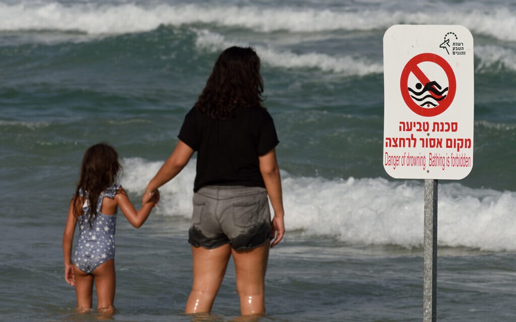 אילוסטרציה: אישה וילדה מול שלט אזהרה בחוף בית ינאי, 25 באוגוסט 2017 (צילום: Gili Yaari/Flash90)