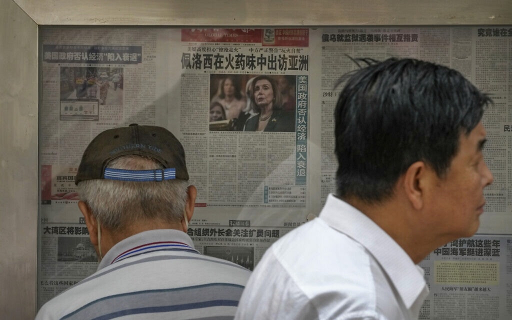 עוברי אורח בבייג&#039;ינג חולפים על פני דוכן עיתונים המציג עיתון יומי ובו ידיעה על הביקור של ננסי פלוסי בטאיוון, 31 ביולי 2022 (צילום: AP Photo/Andy Wong)