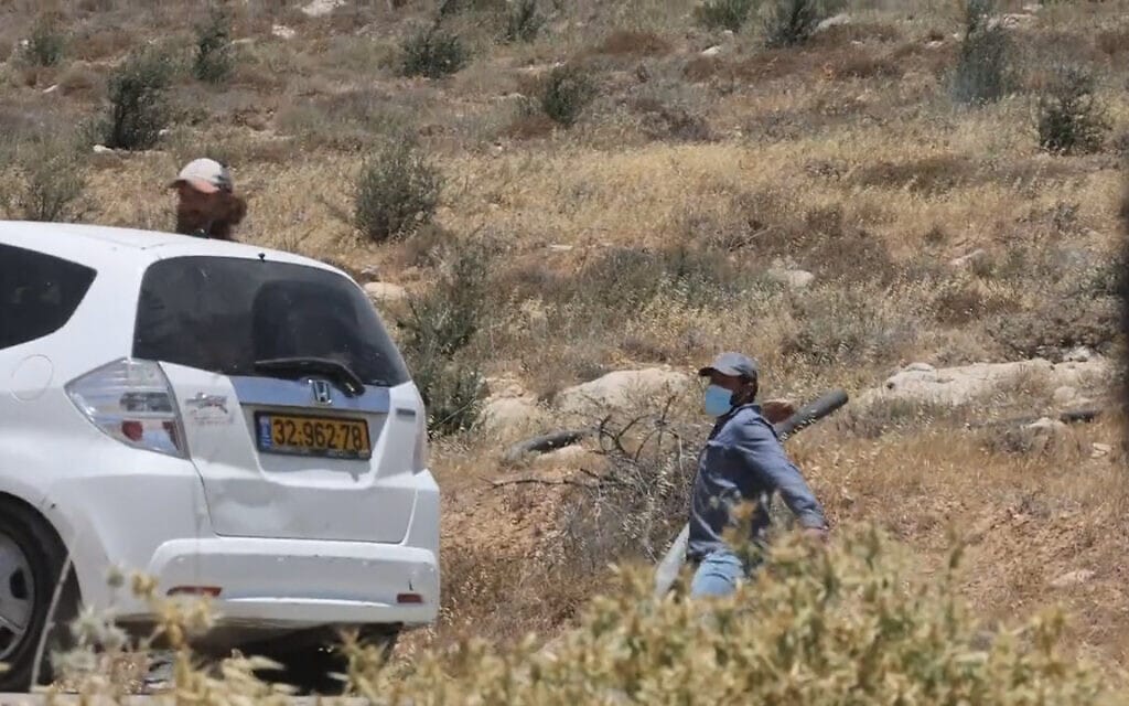 מתנחל ישראלי משליך אבן לעבר פעילי שמאל ליד המאחז הבלתי חוקי מצפה יאיר, הגדה המערבית, 10 ביוני 2022 (צילום: צילום מסך מטוויטר)