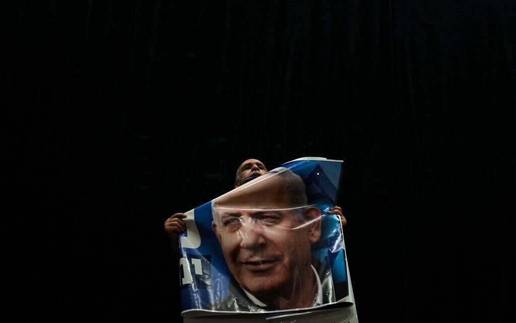 תומך ליכוד מחזיק בפוסטר של בנימין נתניהו בעצרת בחירות במגדל העמק, 23 באוקטובר 2022 (צילום: AP Photo/Ariel Schalit)