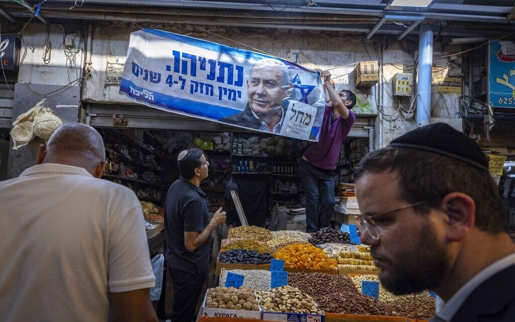פעיל תולה שלט של הליכוד בשוק מחנה יהודה בירושלים, 31 באוקטובר 2022 (צילום: אוליבייה פיטוסי, פלאש 90)