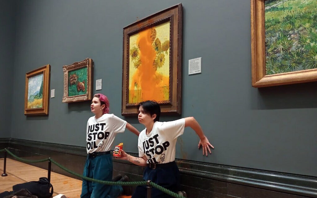 פעילות מחאת אקלים הדביקו את כף ידן לקיר אחרי שהשליכו מרק עגבניות על הציור "חמניות" של וינסנט ואן גוך, בגלריה הלאומית בלונדון, 14 באוקטובר 2022 (צילום: Just Stop Oil)