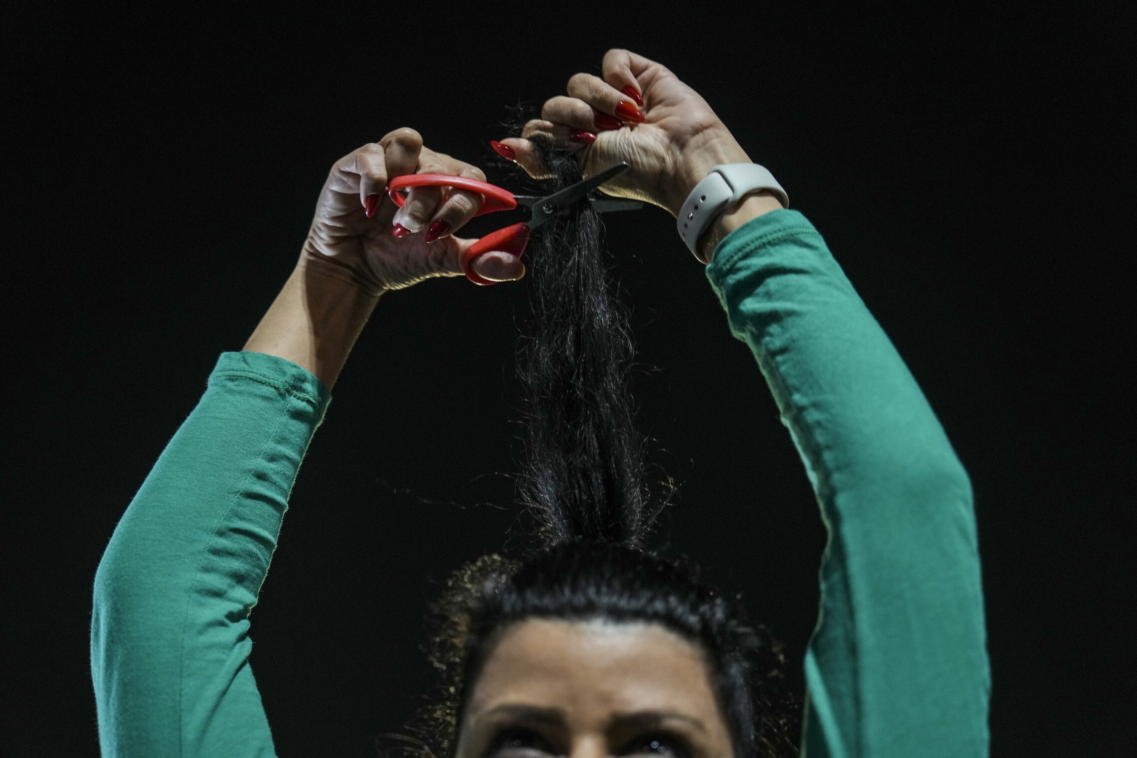 אישה חותכת את שערה בהפגנה בישראל כאות הזדהות עם המחאה באיראן, 29 באוקטובר 2022 (צילום: AP Photo/Ariel Schalit)