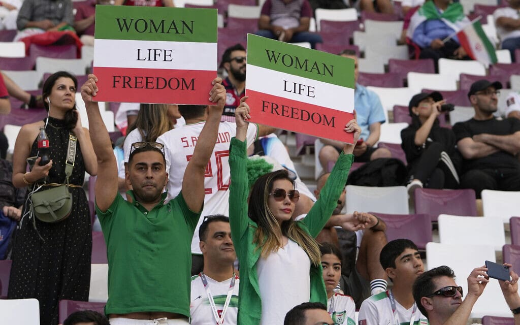 אוהדים של נבחרת איראן בכדורגל מניפים שלטים לאות תמיכה במחאה בארצם באצטדיון הבינלאומי חליפה בדוחה שבקטר, 21 בנובמבר 2022 (צילום: Alessandra Tarantino, AP)