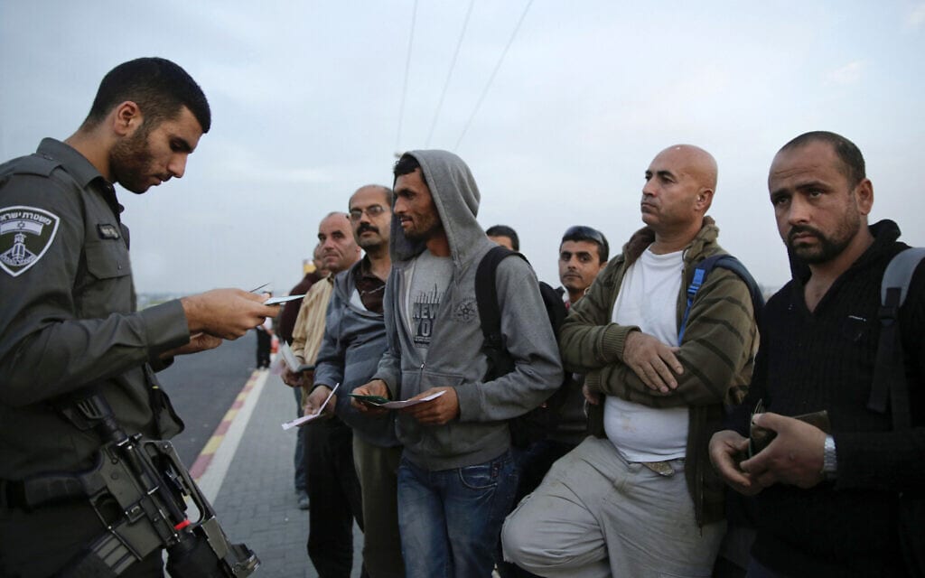 שוטר בודק תעודות זהות והיתרי העבודה של פלסטינים ליד אשקלון, 11 בנובמבר 2014 (צילום: AP Photo/Tsafrir Abayov)