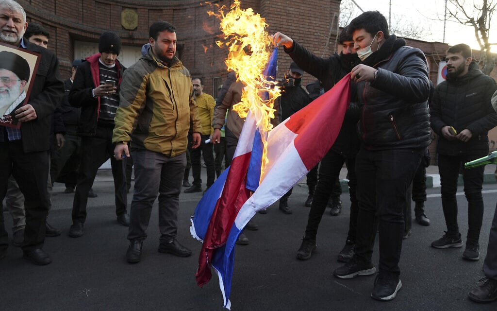 מפגינים שורפים את דגל צרפת באיראן בעקבות הקריקטורה שהופיעה במגזין &quot;שרלי הבדו&quot; של האייתוללה עלי חמינאי, 8 בינואר 2023 (צילום: AP Photo/Vahid Salemi)