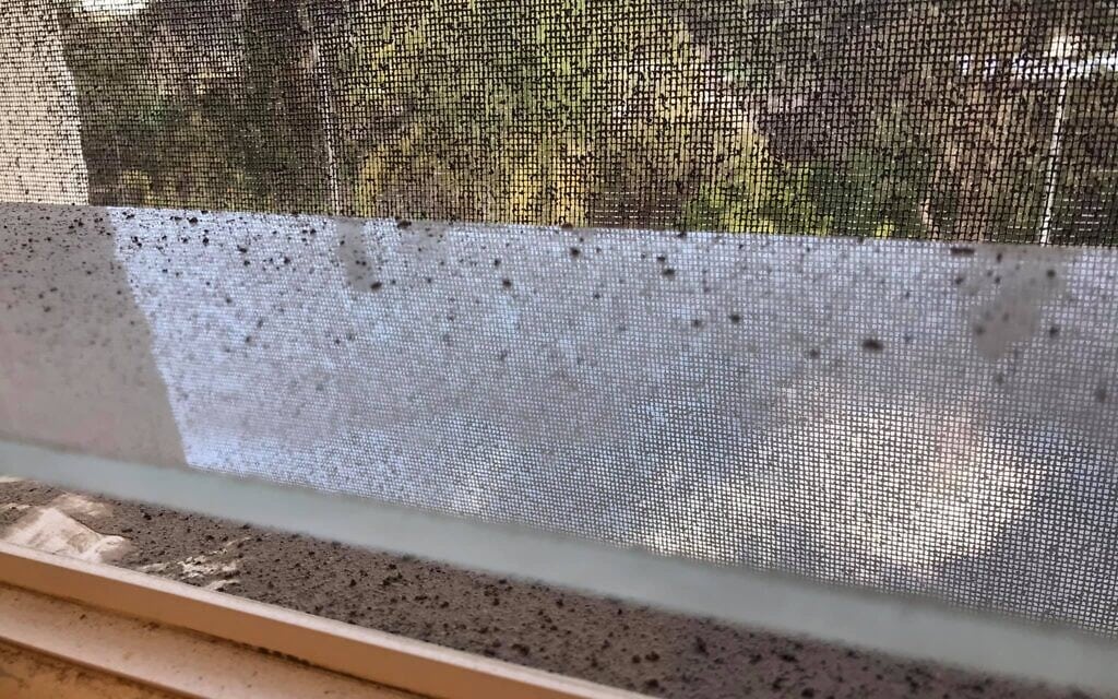 זיהום שהצטבר בחלון של שכן הגר בסמוך לשלושה בתים בהם מותקנים קמיני עץ (צילום: עמותת נושמים נקי)