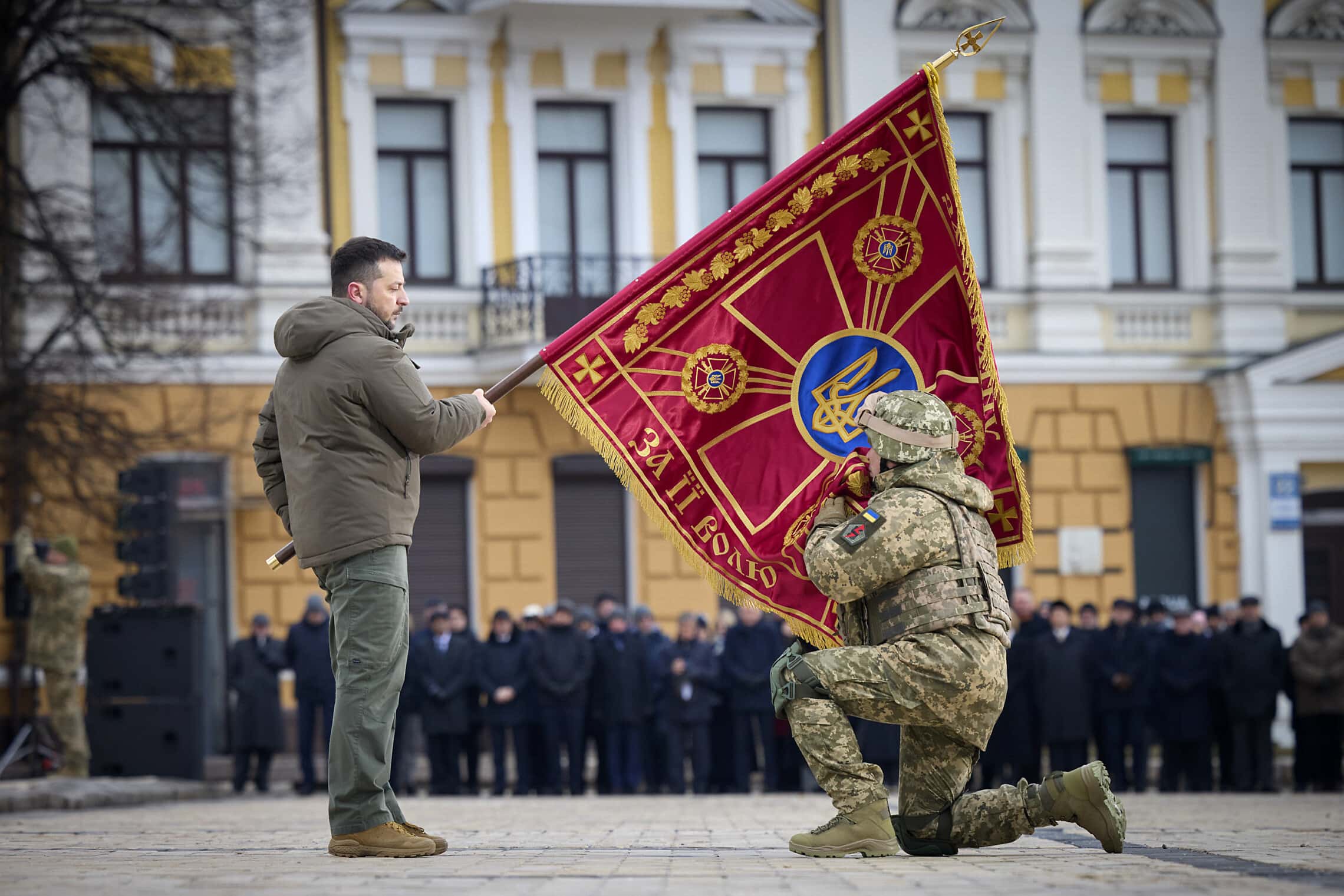 נשיא אוקראינה וולודימיר זלנסקי מחזיק דגל של יחידה צבאית באירוע לציון שנה לפלישה הרוסית למדינה. קייב, 24 בפברואר 2023 (צילום: Ukrainian Presidential Press Office via AP)