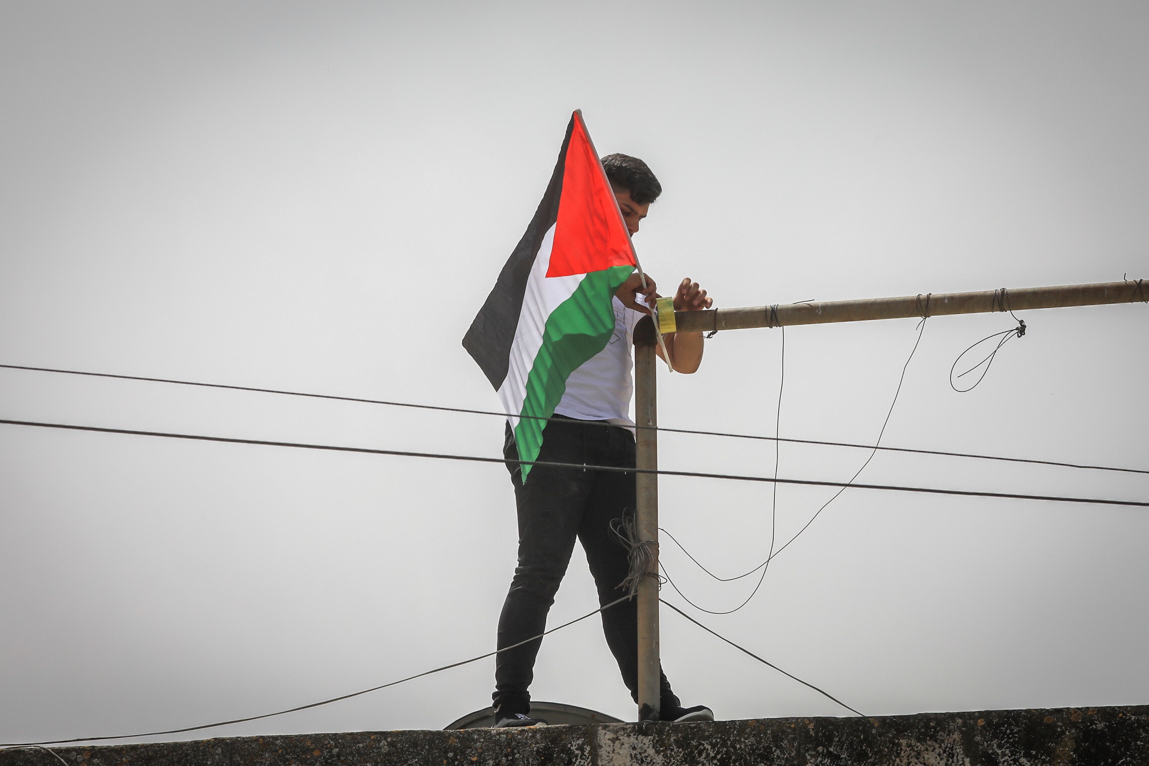 נער תולה דגל של אש&quot;ף בשכונת בית חנינה במזרח ירושלים, אילוסטרציה. למצולם אין קשר לנאמר בכתבה (צילום: Jamal Awad/Flash90)