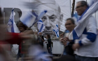מפגינים נגד המהפכה המשפטית חולפים על פני כרזה עם תמונה של ראש הממשלה בנימין נתניהו, 25 במרץ 2023 (צילום: AP Photo/Oded Balilty) מפגינים נגד המהפכה המשפטית חולפים על פני כרזה עם תמונה של ראש הממשלה בנימין נתניהו, 25 במרץ 2023 (צילום: AP Photo/Oded Balilty)