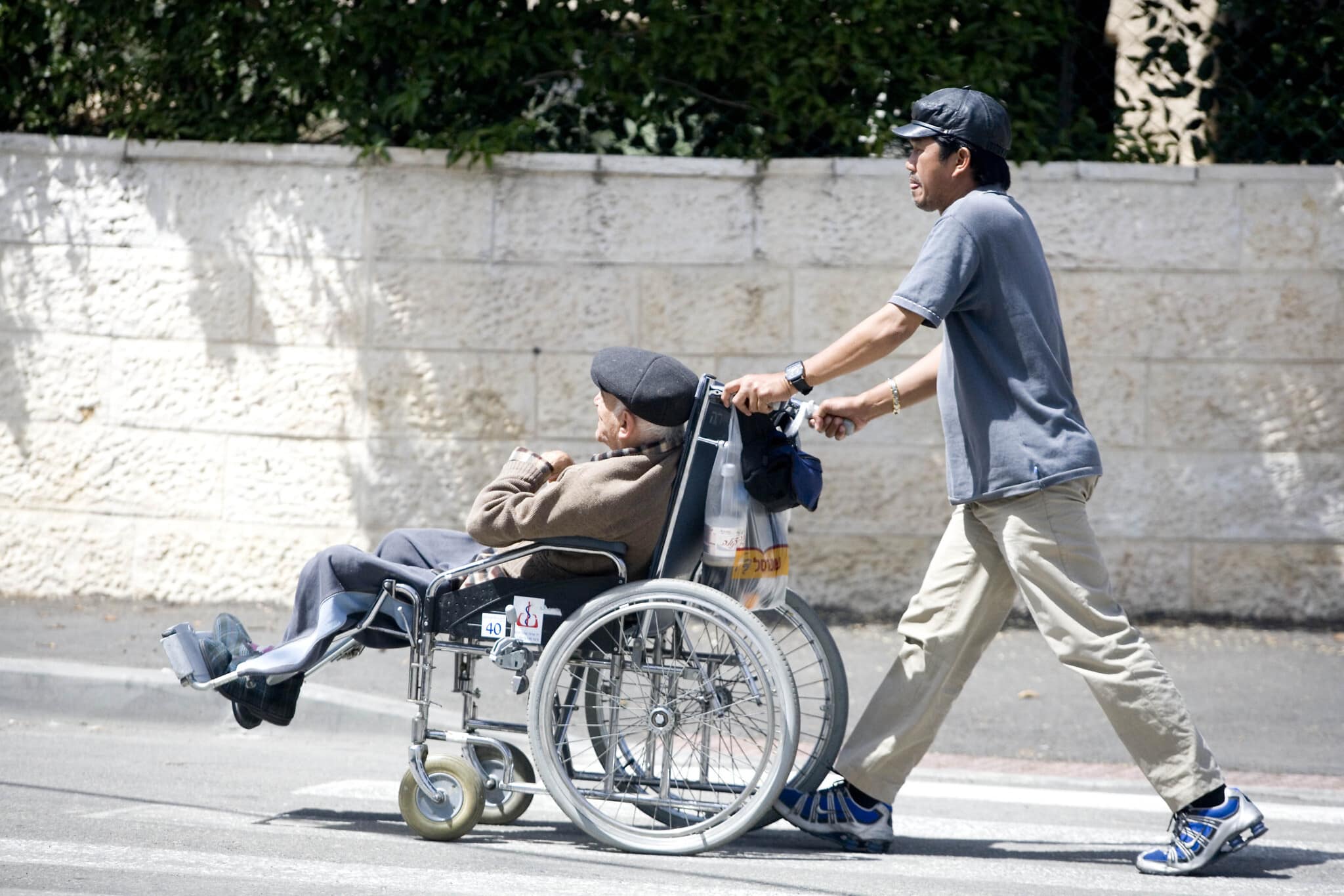 אילוסטרציה: גבר פיליפיני מטפל בקשיש ישראלי היושב בכיסא גלגלים (צילום: Abir Sultan/Flash90)
