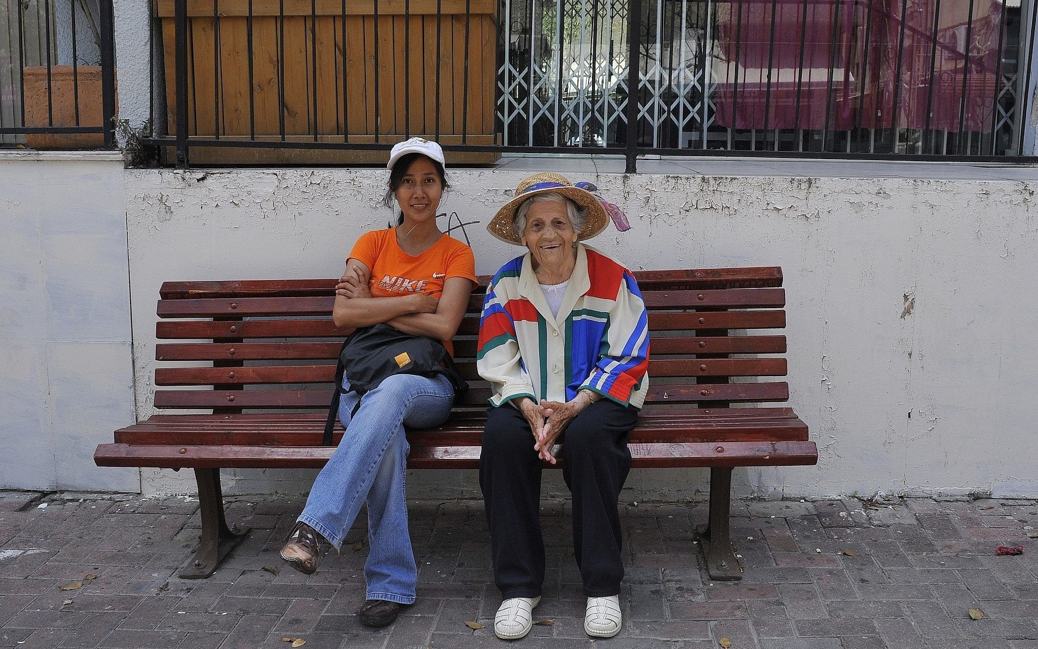 אילוסטרציה: עובדת פיליפינית יושבת על ספסל עם קשישה ישראלית, 20 במאי 2009