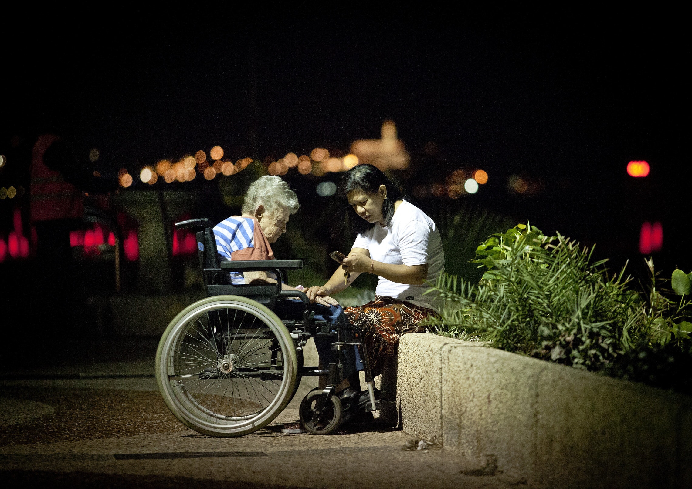 אילוסטרציה: מטפלת פיליפינית עם קשישה ישראלית בטיילת של תל אביב (צילום: Moshe Shai/FLASH90)