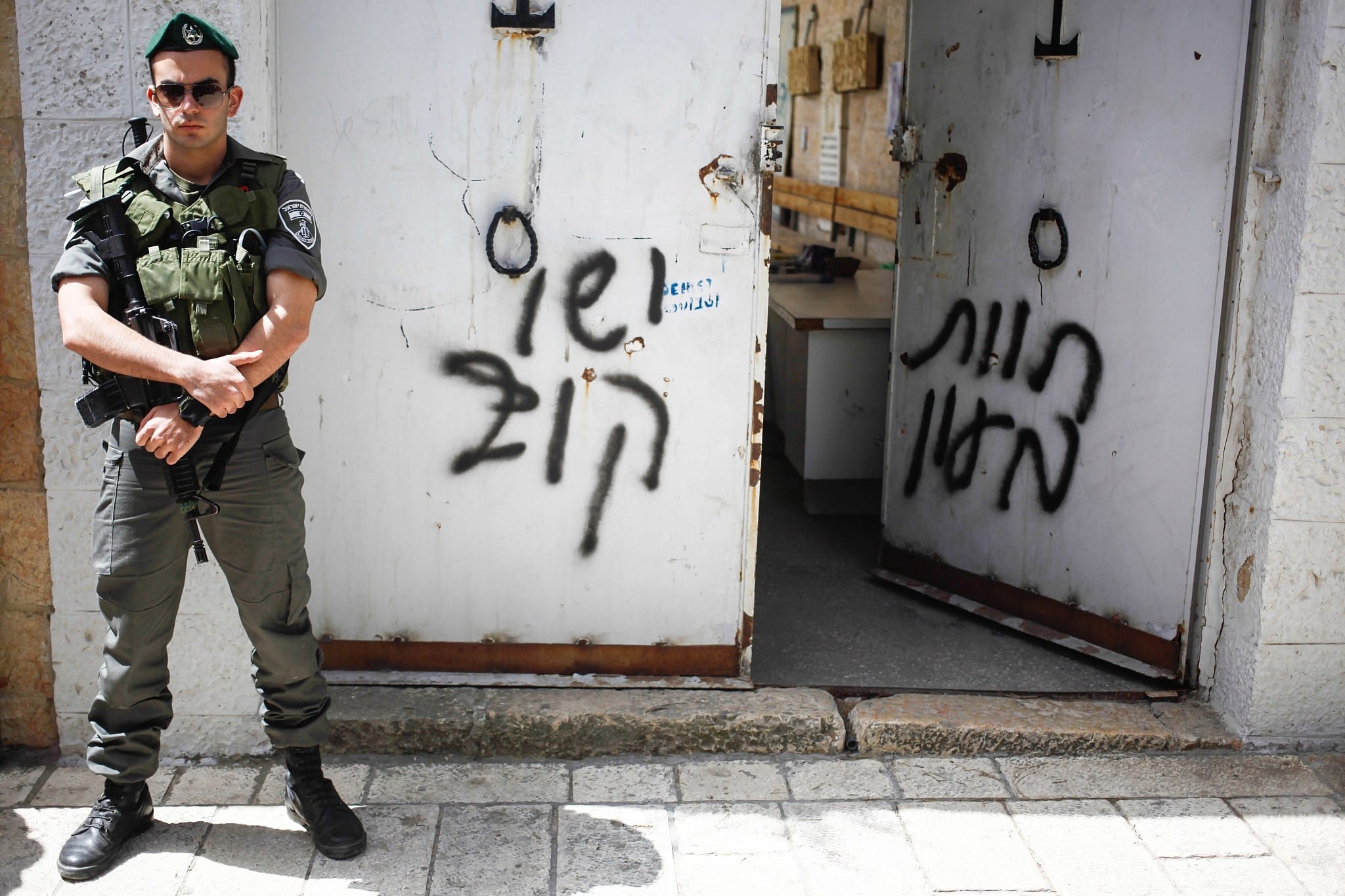 שוטר משמר הגבול עומד ליד כתובת שרוססה על כנסיית הדורמיציון בירושלים, 31 במאי 2013 (צילום: פלאש90)